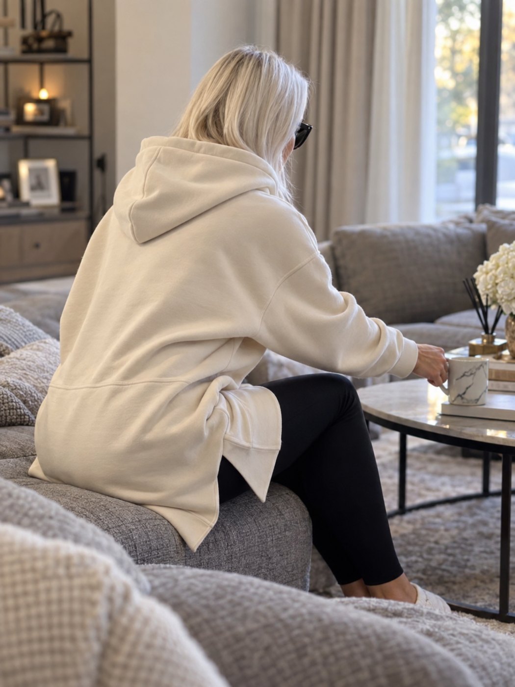 Seated woman in the cream Warmy hoodie dress, hem covering her thighs